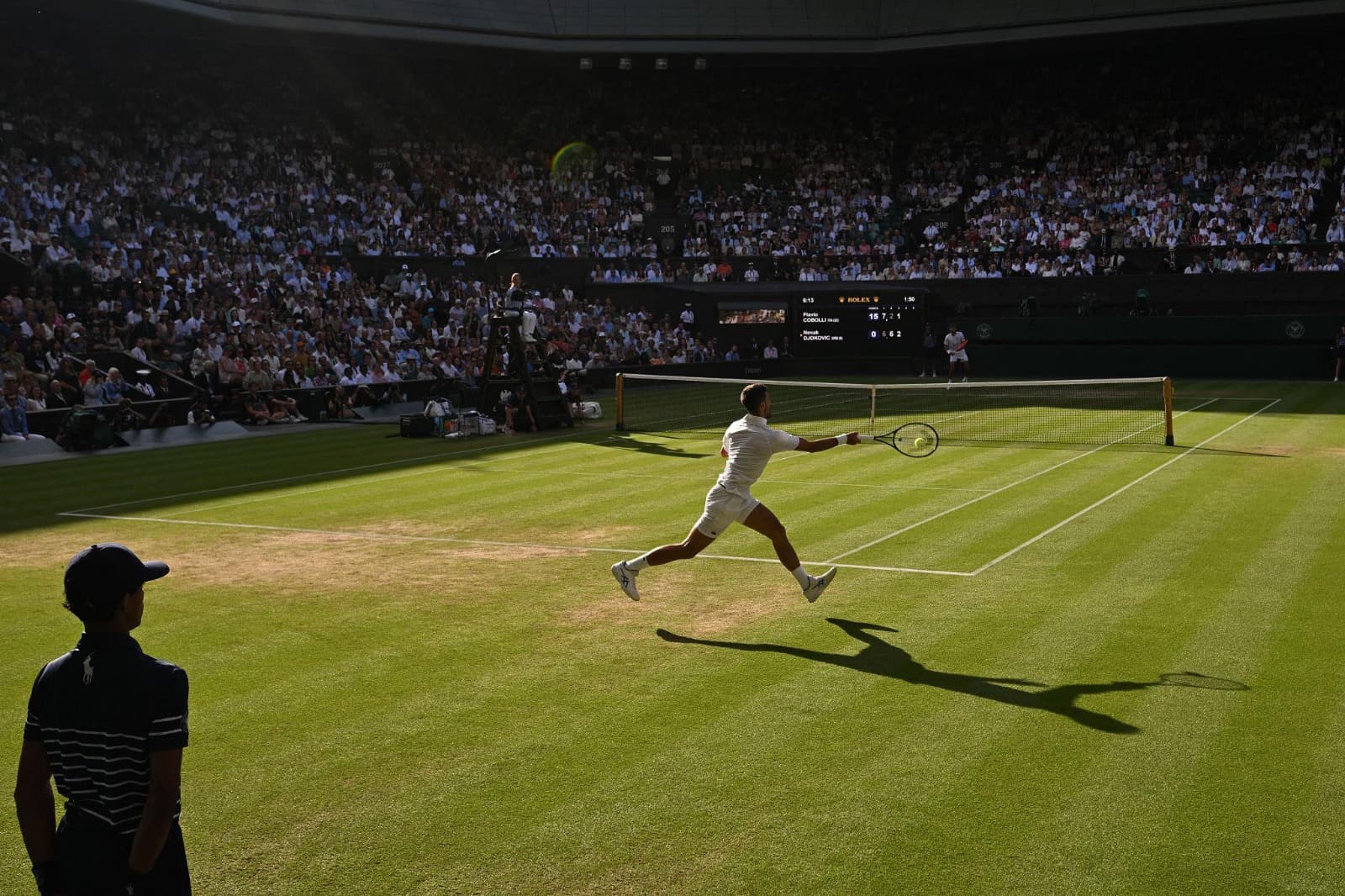 Tennista in allungo su un campo in erba durante una partita
